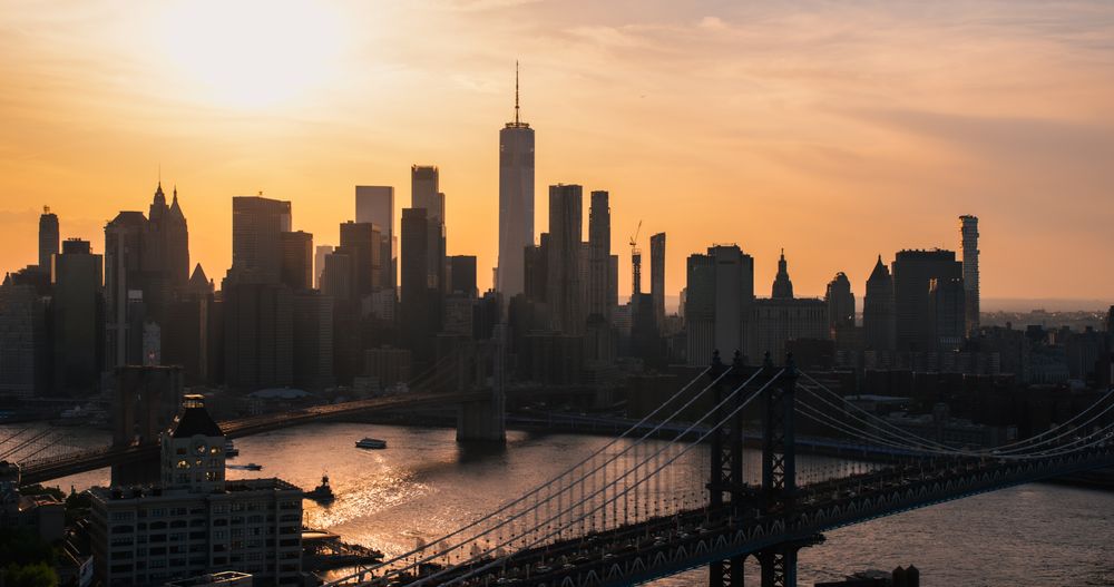 New York City Skyline Aerial Photo from a Helicopter at Sunset. Famous Skyscraper Buildings with Manhattan and Brooklyn Bridges. Busy Diverse Megapolis with Cars, Boats and People Moving Around