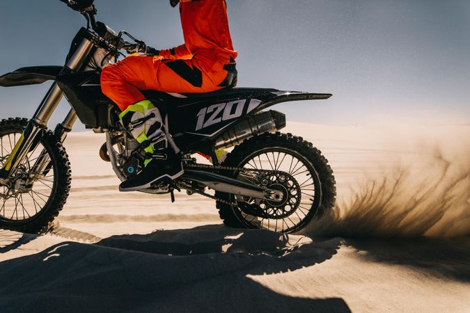 Motocross rider going full throttle over sand dune