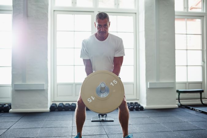 Man lifting heavy weights in bright gym
