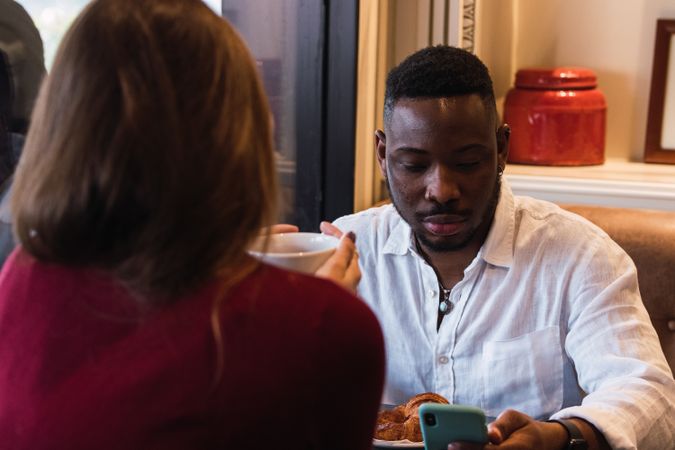 Multiracial couple having breakfast in cozy cafe