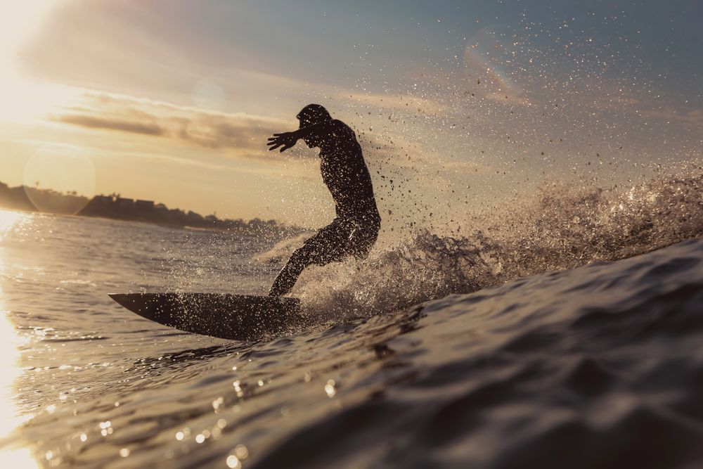 Man on surf board on waving water at sunset