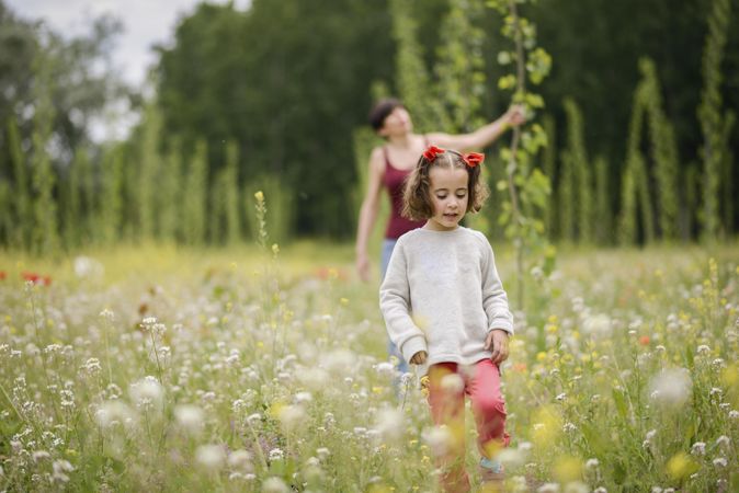 Little girl walking ahead of her mother in field