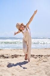 Cheerful boy running on beach with hands wide open like airplane