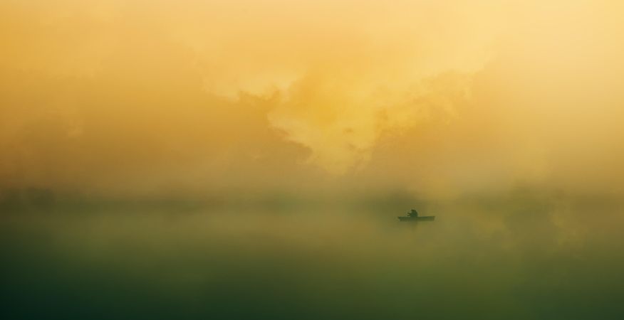 Silhouette of person in paddle boat in mist