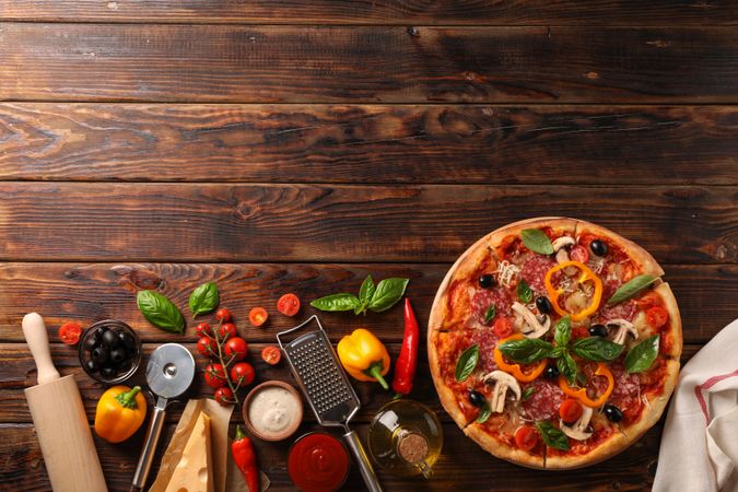 Delicious pizza and ingredients on wooden background, copy space