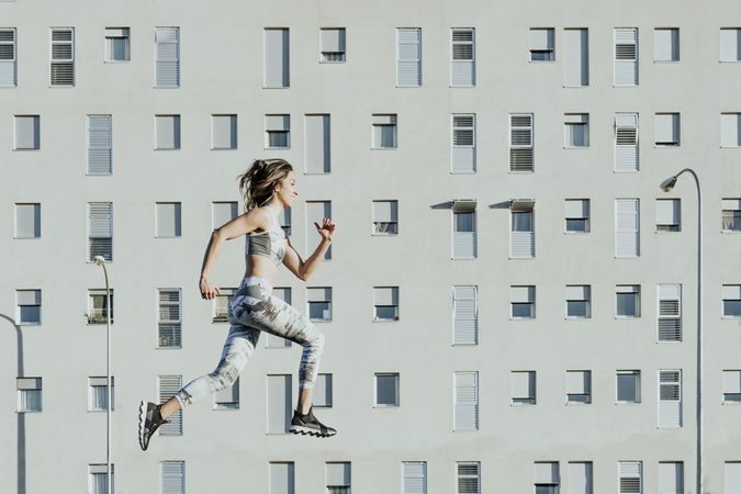 Woman in sportswear jumping near building