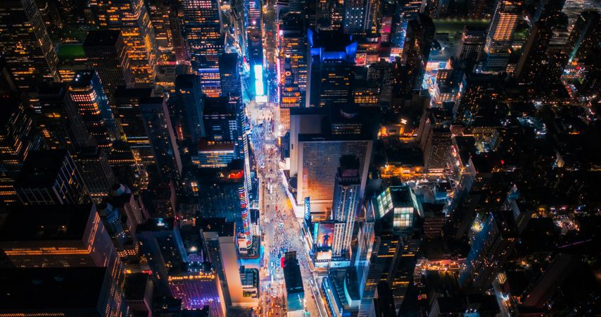 Night Aerial Photo of New York City with Skyscraper Spires and Straight Busy Streets with Cars and Yellow Taxi Vehicles. Lowered Helicopter View of Office Buildings in a Big Urban Center