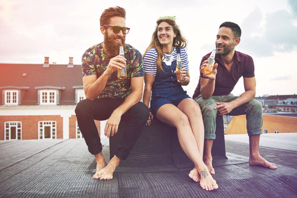 Three friends relaxing outside on a rooftop with beer