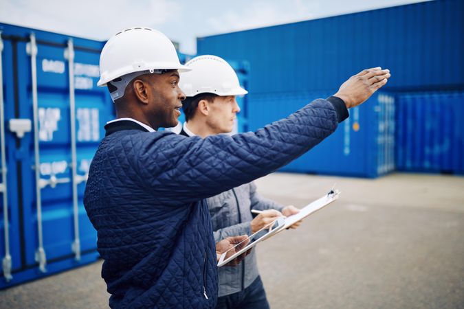 Two men in hard hats on site discussing a construction project