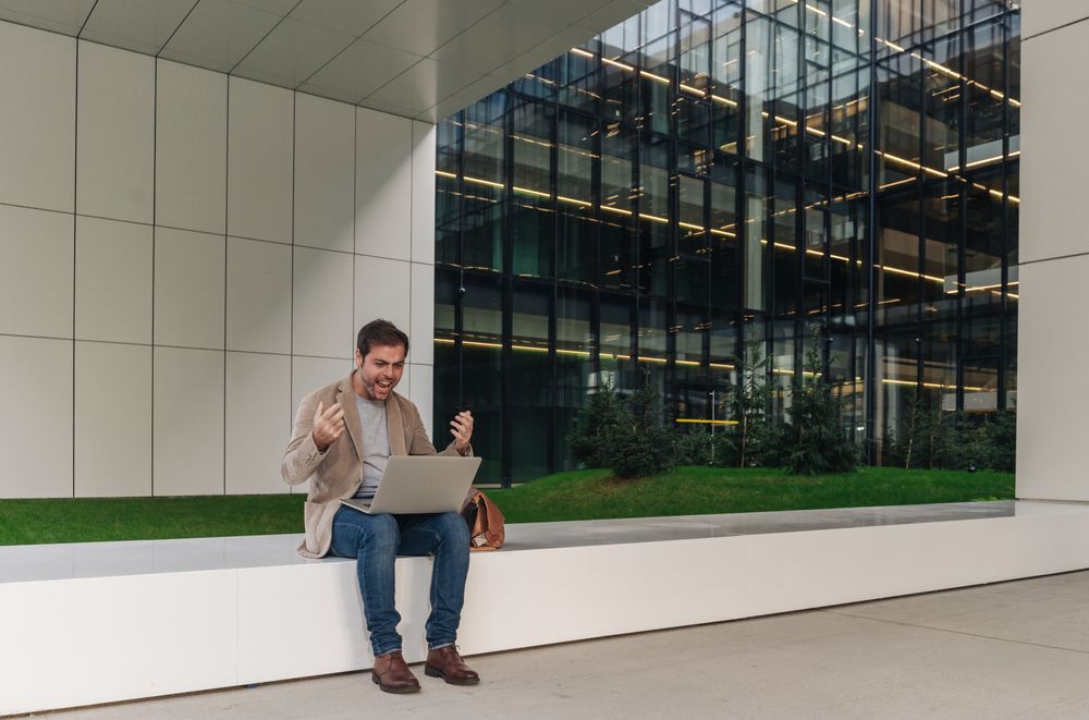 Cheerful businessman using laptop on street