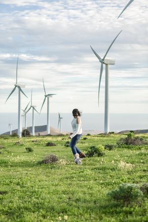 Woman running on green grass nearby wind turbine farm in Lanzarote, Spain