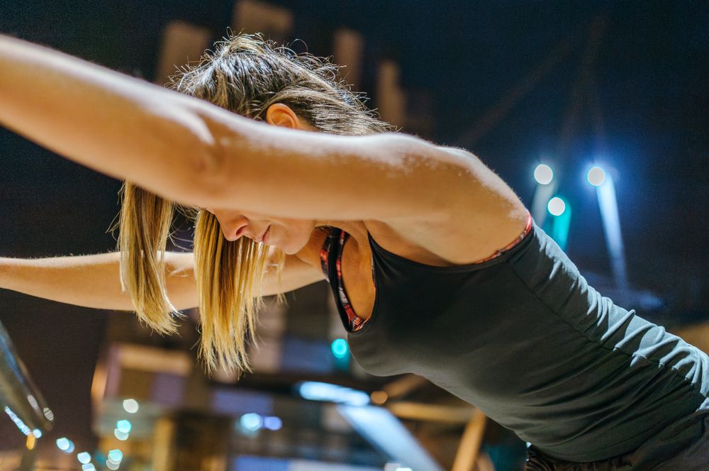 Unrecognizable exhausted female runner resting after training at night