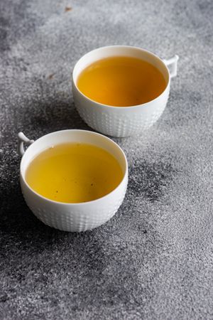 Two cups of green tea on grey counter