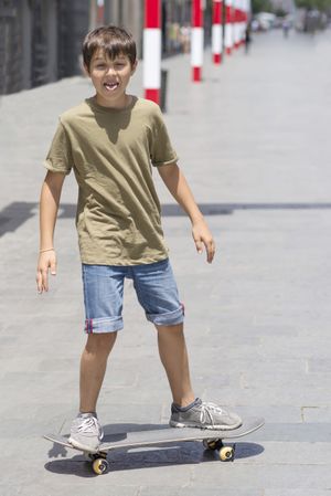 Little boy with a skateboard making a funny face