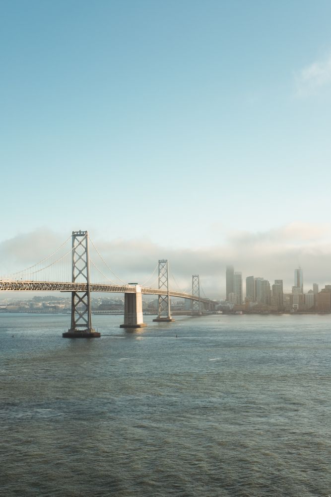 Long bridge construction over wavy water to city