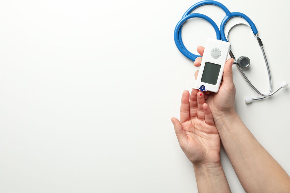 Female checking blood sugar level on blank background