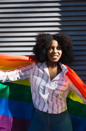 Fun Black woman posing happily with the LGBT flag