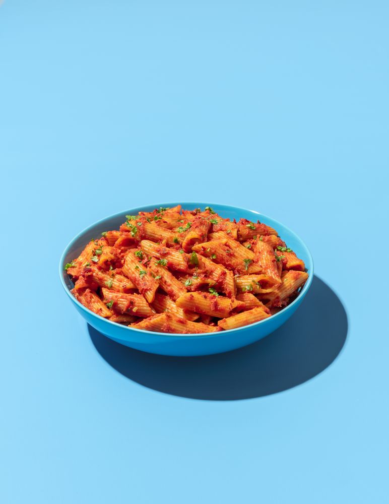 Penne pasta bowl isolated on a blue background