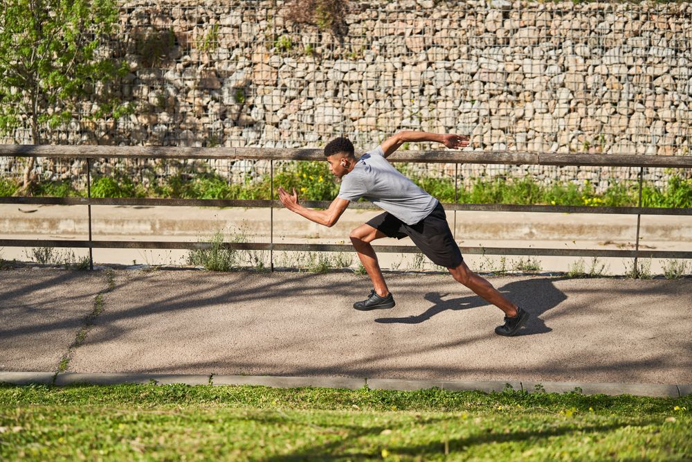 Athletic man running on asphalt path in summer