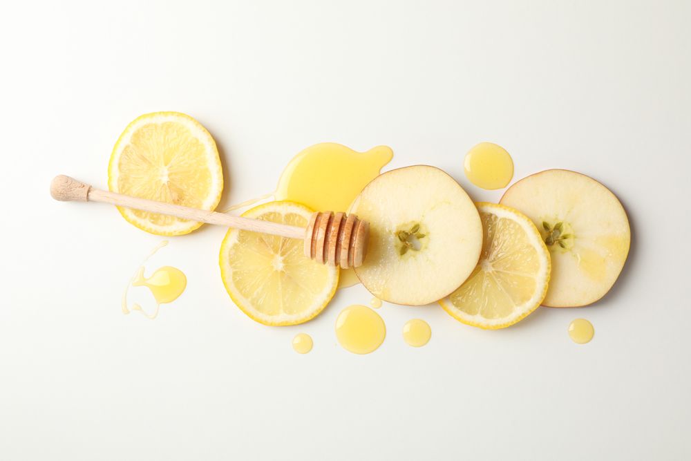 Dipper, honey, apple and lemon slices on blank background, top view