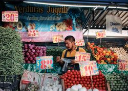 Man behind vegetable stall at market