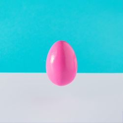 Pink egg suspended on blue background