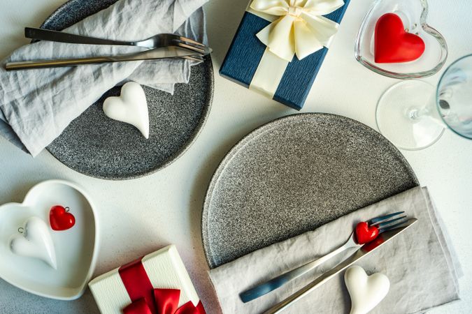 Top view of two grey plates with champagne flutes, hearts and presents