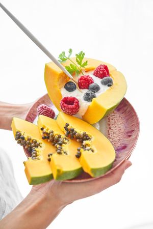 Crop person with plate of papaya dessert