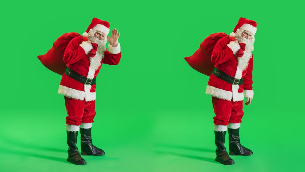 Studio Shot Isolated Mockup Template: Jolly Santa Claus with a Bag with Gifts For All Good Children On Green Screen Chromakey Background And Waving To Camera. Christmas And New Year