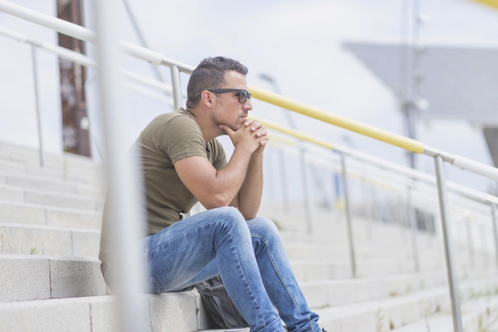 Side view of male sitting on stairs deep in thought