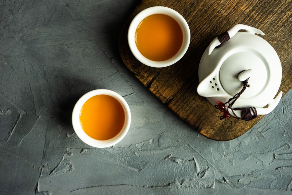 Top view of teapot and two cups on grey counter with copy space