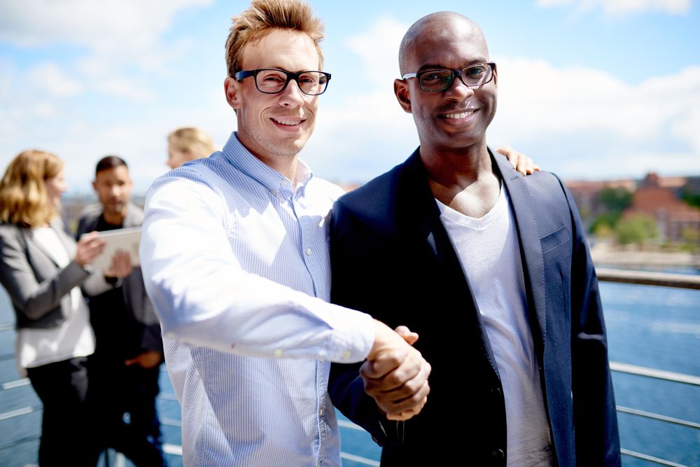 Two happy businessman shaking hands outside