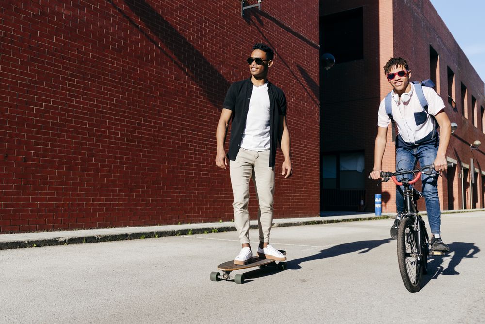 Young Black men riding bicycle and skateboard