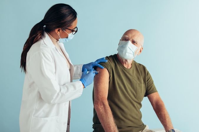 Female doctor giving coronavirus vaccine to older man