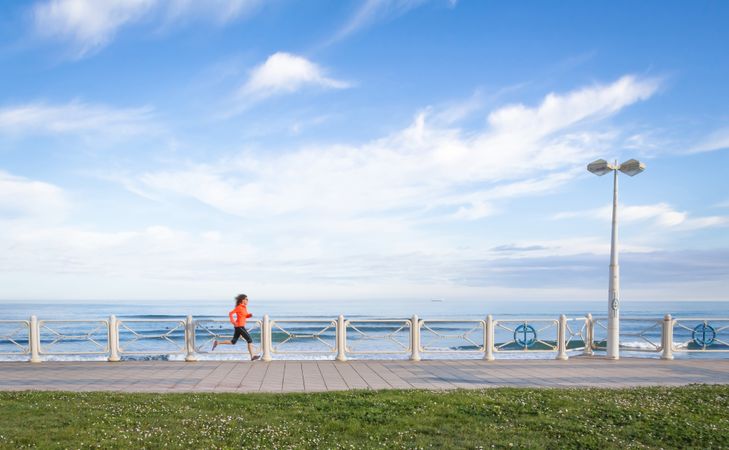 Athletic woman running on beach promenade on a summer morning