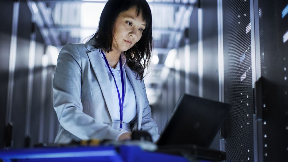Asian Female IT Engineer Working on a Laptop on Tool Cart, She Scans Hard Drives.