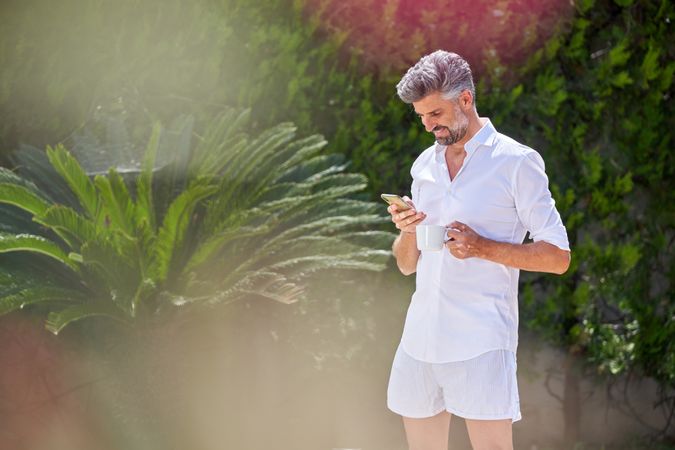Mature man using smartphone in backyard