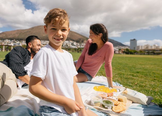 Family sitting in a park with snacks for picnic