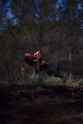Woman doing Parivritta Utkatasana posture in forest