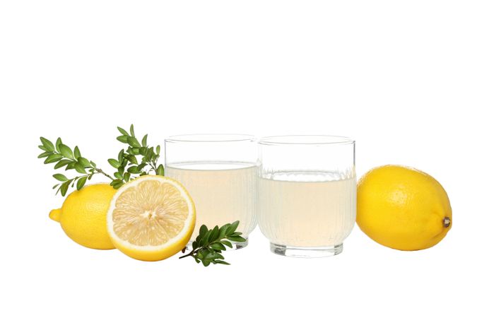 Lemons, branches and glasses with limoncello, isolated on light background
