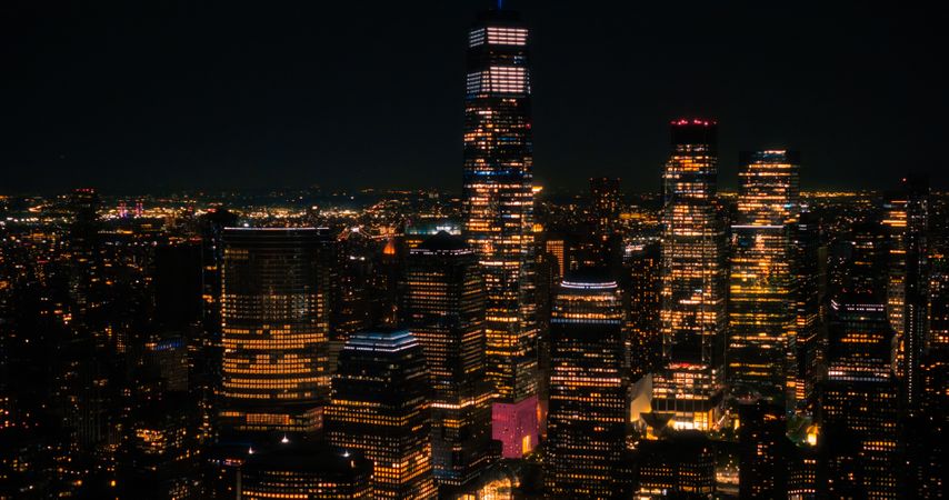 Aerial Helicopter Cinematic Night Scene with a Panoramic View with One World Trade Center Skyscraper and Vibrant Cityscape. Beautiful Office Buildings with Indoors Lights