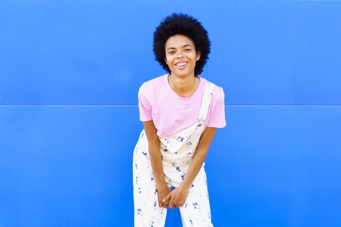 Smiling woman leaning forward in floral overalls