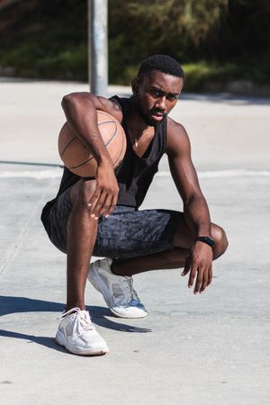 Confident Black sportsman on basketball court in summer