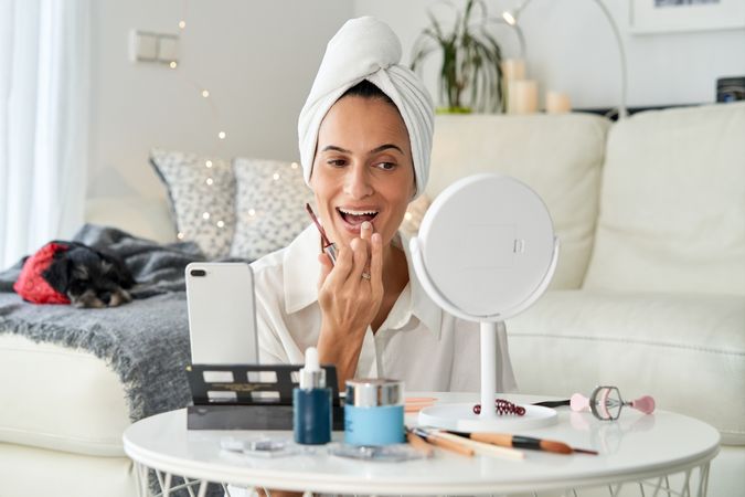 Woman blogger applying liquid lipstick on lips while recording v