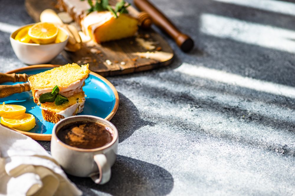 Homemade lemon cake with fresh mint served on blue plate with coffee