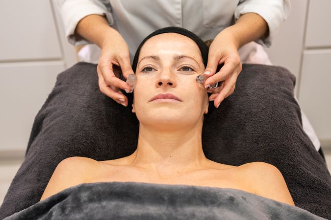 Female beautician massaging face of client with stones