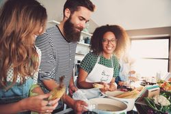 Black woman smiling in the kitchen with her friends as she boils pasta