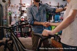 Man with tattoos shaking hands in a bike shop bEPQ74
