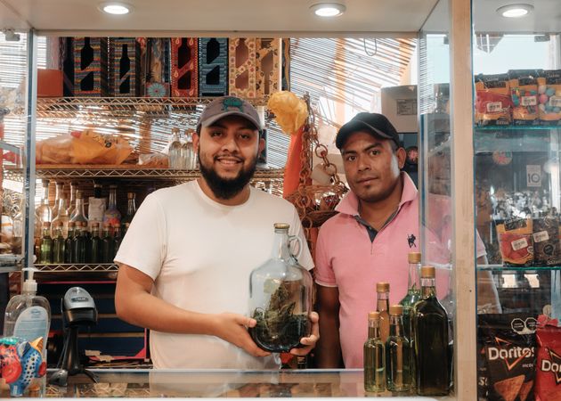 Two men in store in Oaxaca with large vat of herbal tincture