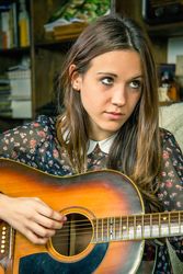 Young hipster woman playing acoustic guitar at home